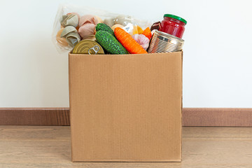 Coronavirus food donation box, closeup of bright vegetables, pasta, canned food. Contactless delivery.