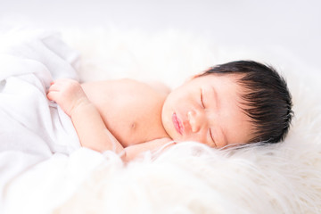 Obraz na płótnie Canvas A newborn cute baby. Newborn child wearing white cotton fluffy. Infant baby girl sleeping in bed.