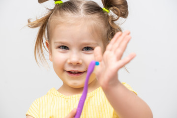 little girl smiles and holds forward a toothbrush