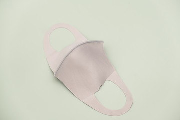 Beige fabric protection face mask isolated with light green background- Stock photo