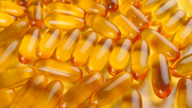 Many fish oil capsules on table, closeup