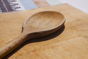 Country style kitchen appliencies - big wooden spoon and wooden cutting board on linen table cover.