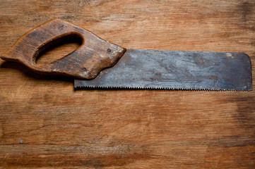 Old vintage saw of the last century extracted from the chest in the workshop of grandfather. Background for craftsmanship and manual labor.