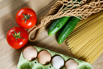 Food for the poor: pasta, cucumbers, tomato, eggs on a wooden table