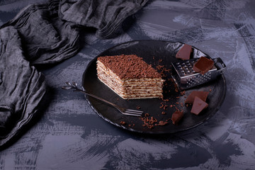 Mikado cake with caramel and chocolate buttercream on the black ceramic plate. Armenian cuisine...