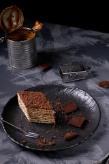 Mikado cake with caramel and chocolate buttercream on the black ceramic plate. Armenian cuisine...