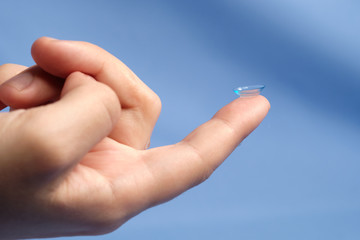Contact lenses on the fingertip on a blue background, space for text
