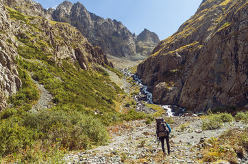 Fototapeta na wymiar A lonely traveler slimbing up the mountain trail near the river.