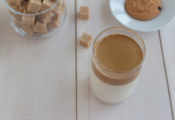 Dalgona coffee cold tasty drink in a glass on a light wooden background