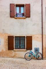 Fototapeta na wymiar Bicycle in the street near wall of old house
