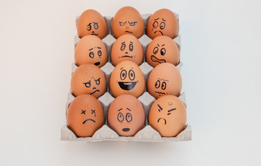 Don't worry be happy. egg in the middle of a group of angry, envious, crying eggs. Idea of positive approach. White background.