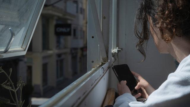 Chica con pelo rizado mirando por la ventana
