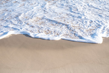 Ocean (sea) foam on the background of yellow sand on a sunny day.