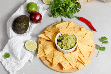Guacamole sauce with nachos on a round wooden plate