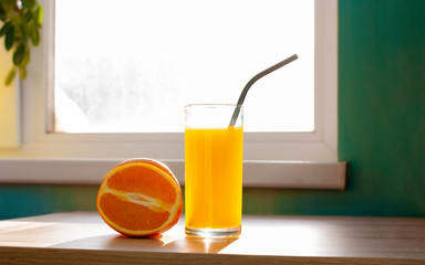 Beautiful orange fruit and glass of juice with iron nont plastic tubule near the window on table lifestile picture