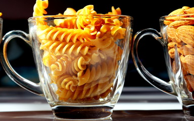 A closeup photo of golden fusilli pasta in a transparent glass mug