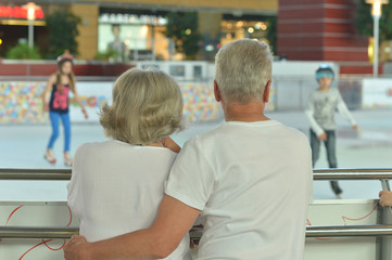 Beautiful happy mature couple looking on skating ring