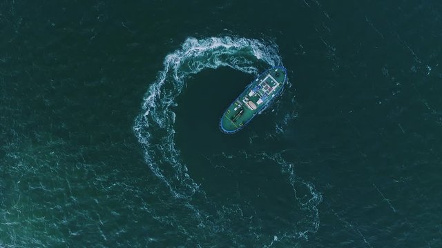 The view top the tug moves in a circle creating beautiful circular waves, the deep blue sea