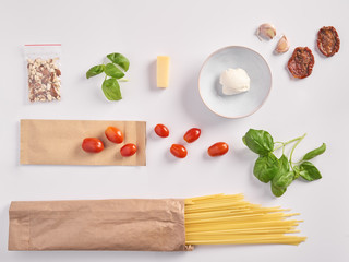 A set of products for an Italian dinner: spaghetti pasta, cherry tomatoes, basil, garlic, cream cheese on a white background. Dinner Set Food Delivery
