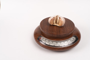 garlic lies on kitchen scales. white background