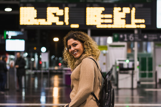 Side view of beautiful happy woman looking at camera with backpack in airport terminal