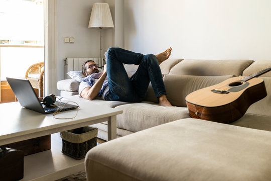 Man writing notes on couch in cozy living room