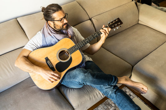Stylish guitarist on couch in living room