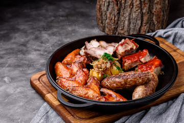 Baked meat in a pan on a concrete background. Beer snack. Close-up. Space for text