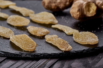 Ginger dried fruit slides spread beautifully on a black plate. side view. on a wooden table. Against viruses and diseases. immune product