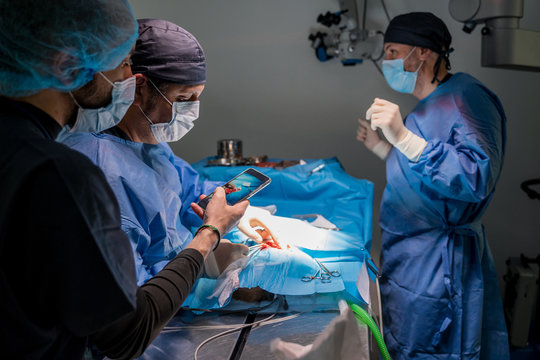 Surgeons and nurses in uniform concentrating and operating patient using special equipment in operating room of contemporary hospital