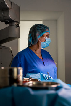 Pensive female doctor in medical uniform looking away while standing against blurred interior in laboratory of contemporary hospital
