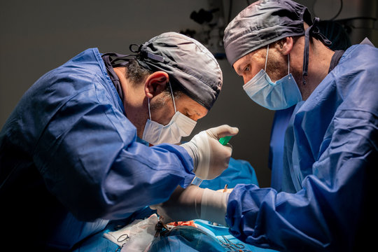 Surgeons and nurses in uniform concentrating and operating patient using special equipment in operating room of contemporary hospital