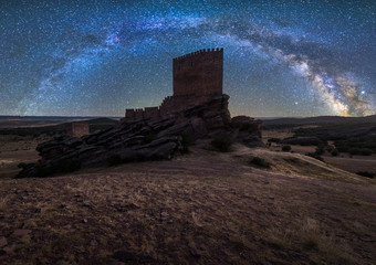 Remains of ancient castle under Milky Way at starry night with lantern light