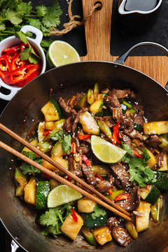 Top view of appetizing oriental spicy stir fry meat with zucchini and red pepper garnished with fresh lime and cilantro