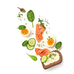 Open sandwich salmon, cucumber, boiled egg, soft cheese flying. Homemade sandwich with rye bread isolated on white background. Levitation fly salmon smorrebrod creative cook concept