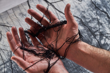 Anonymous man holding tangled thread