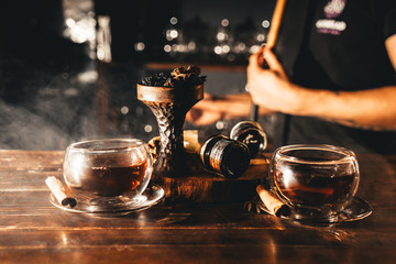 Fototapeta na wymiar Spicy tea with cinnamon and anise with spicy oriental shisha on wooden table