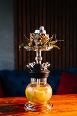 Sweet pineapple shisha with sliced pineapple as a tobacco bowl in a dark oriental atmosphere of lounge bar