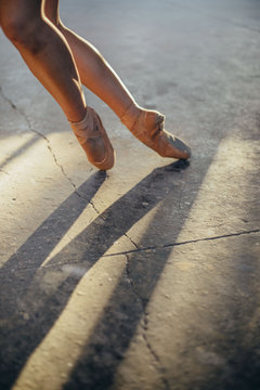 Crop unrecognizable female ballet dancer in pointes with bruise on leg standing on tiptoe while performing classic exercise during training in studio