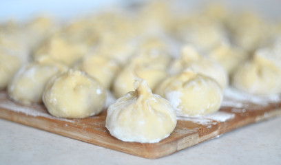 georgian dish meat khinkali uncooked on cutting board with flour with copy space