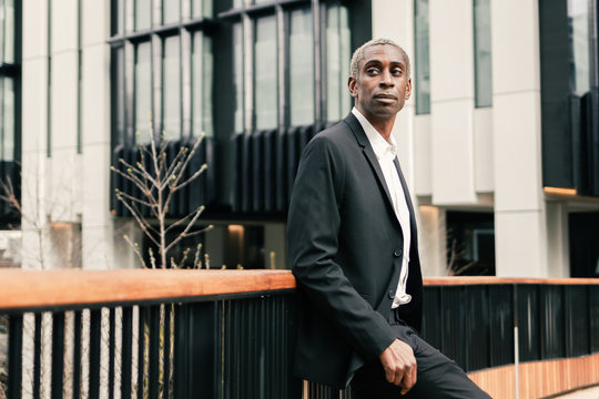 Confident black businessman leaning on railing