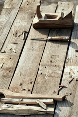 wooden background. On the village table lie dotches, sawdust, and on the background of the bit and jointer plane. vertical picture. Wood thread tool. solar lighting