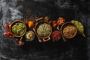 Top view composition with different kinds of natural aromatic spices placed on slate surface background