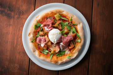 Deliziosa pizza primavera con prosciutto crudo, mozzarella fior di latte, rucola, sugo e pomodoro fresco