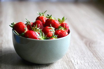 Bowl of fresh strawberries on wooden table. Selective focus.