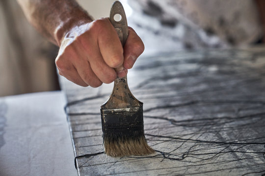 From above of crop male hand with paintbrush painting abstract canvas on blurred background