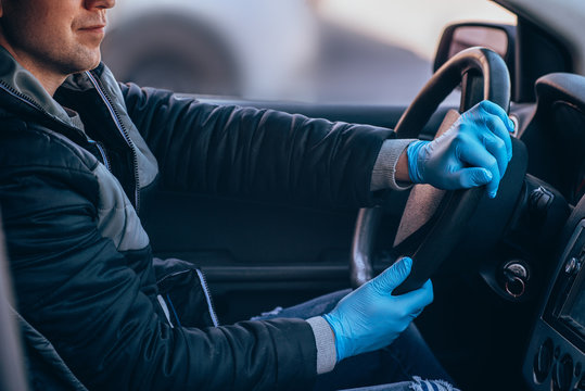 A man driving a car in a protective medical mask and gloves. Safe drive in a taxi during a pandemic coronavirus. Protect the driver and passengers from bacteria and virus infection in quarantine.