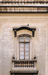 Antique baroque window framed by decorative stucco with a balustrade below on a gray wall. Dominican Cathedral Monastery. Lviv, Ukraine.