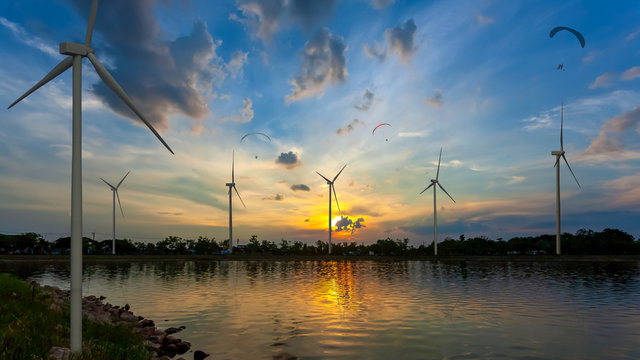 Landscape of Electric wind turbine generator at sunset with Powered Parachute Flying