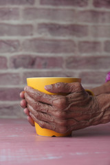 senior women hand holding yellow color mug, 